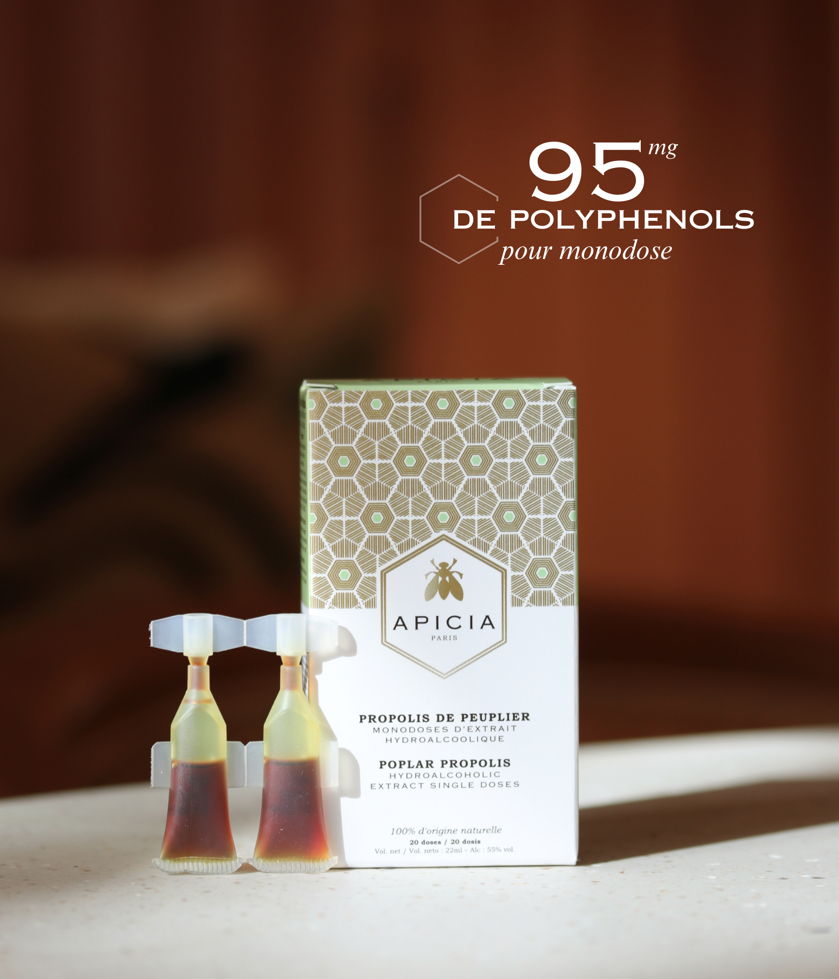 Boîte blanche et dorée, et deux monodoses posées sur son côté gauche, sur une table blanche.