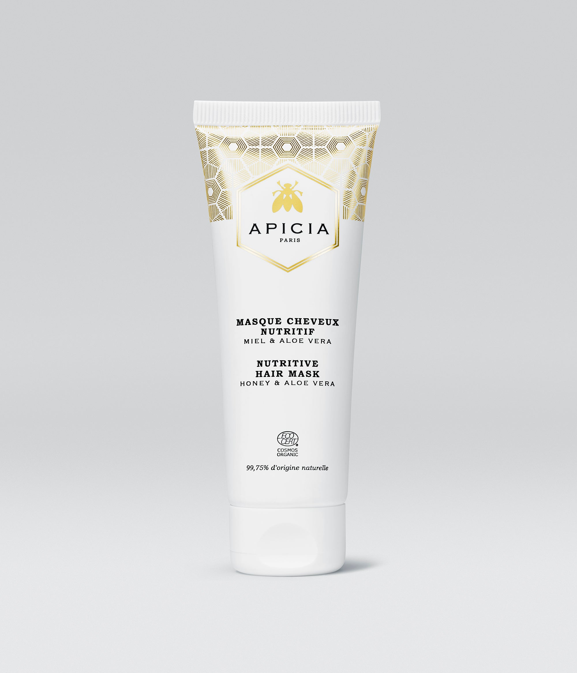 Packshot d’un tube de 75ml blanc et doré de masque cheveux, sur fond gris.