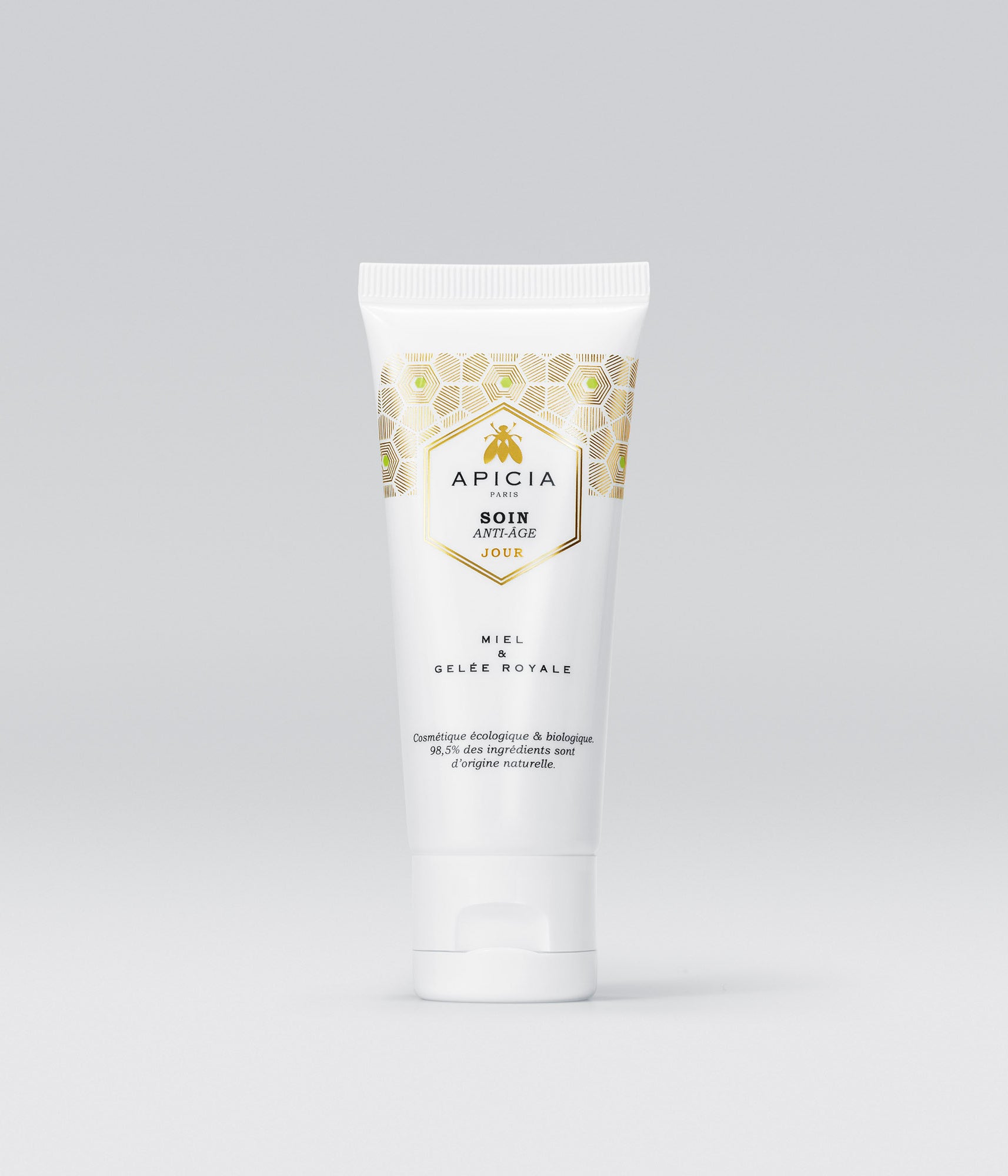 Packshot d’un flacon de creme pour visage blanc et doré sur un fond gris