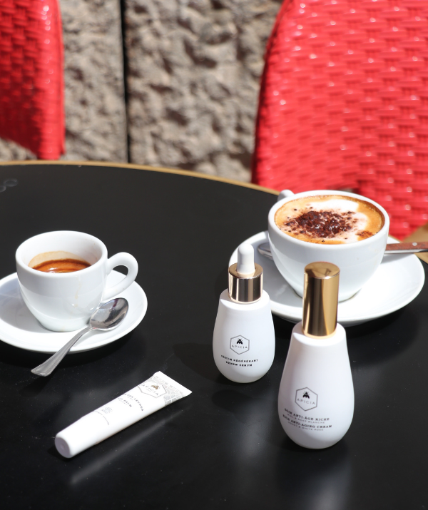 Black table with coffee and 2 white skincare products