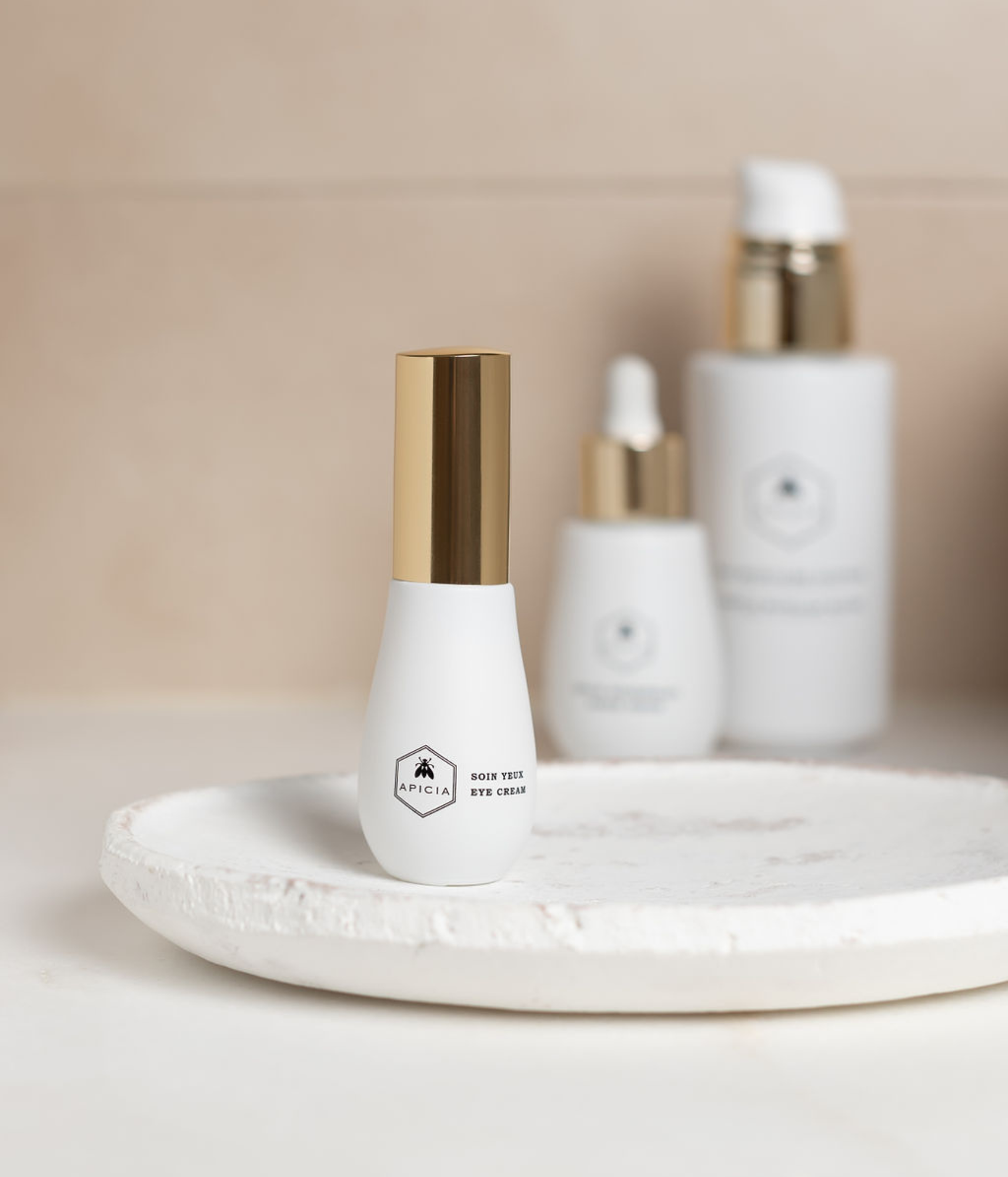 Salle de bain avec un soin contour des yeux blanc et doré, ainsi que deux autres produits de beauté en flacon blanc.